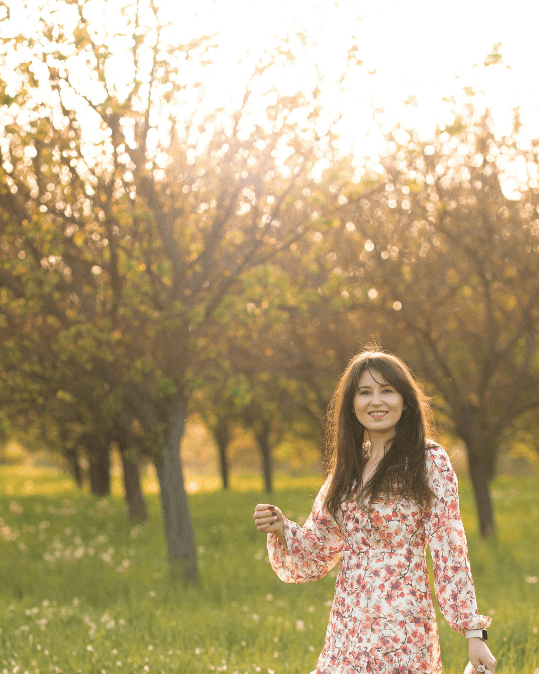 Smiling woman looking at the camera, surrounded by nature.