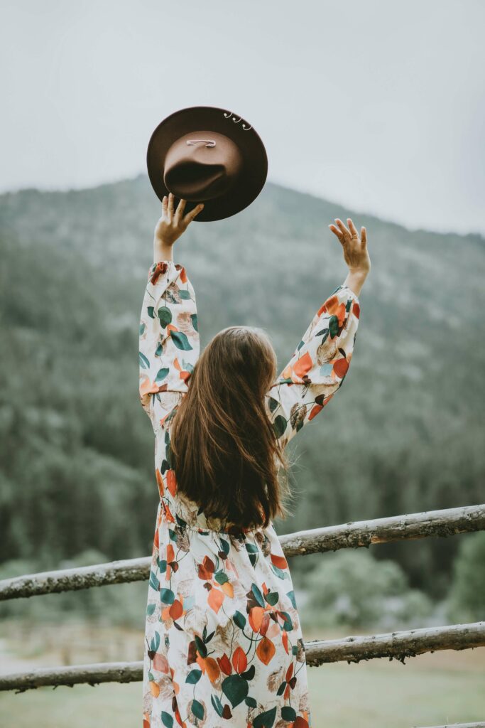 A woman from behind, in the nature, arms in the air, free.